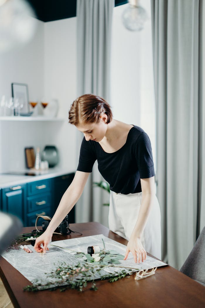 Woman Wearing Black Top and White Bottoms Standing Beside Table